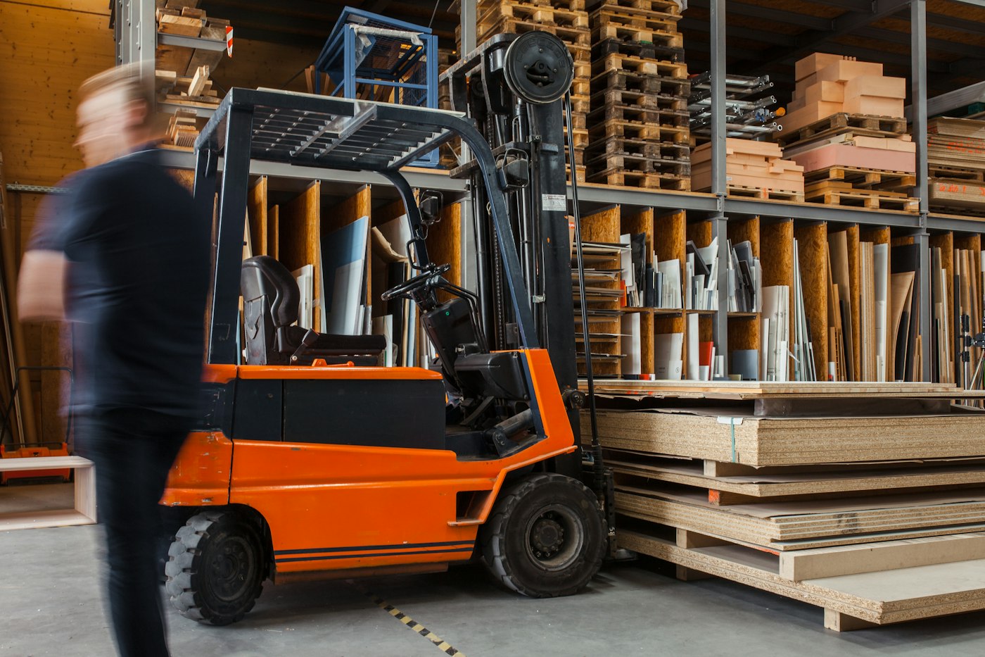 Forklift beside shelves of boards and materials